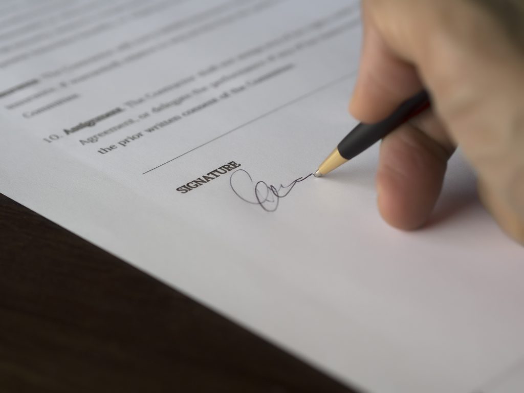 a person signing signature on paper